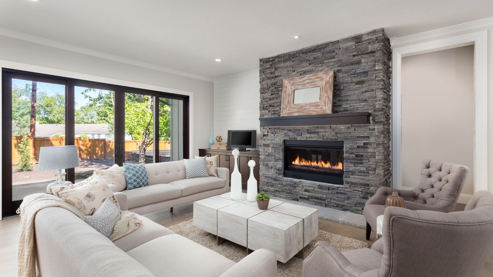 Renovated living room with stacked stone fireplace and neutral furnishings