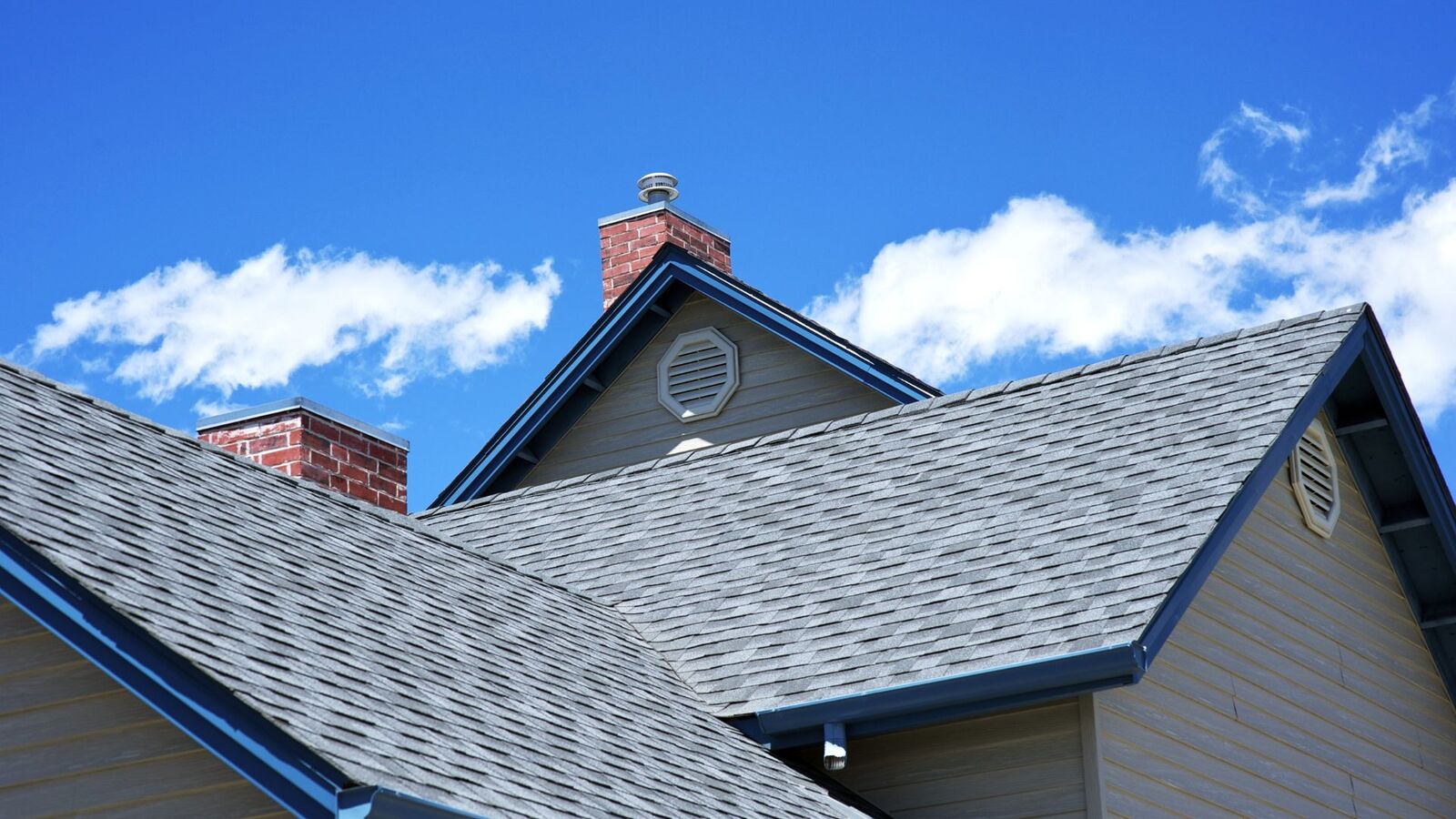 Completed shingle roof replacement under a blue Oklahoma sky
